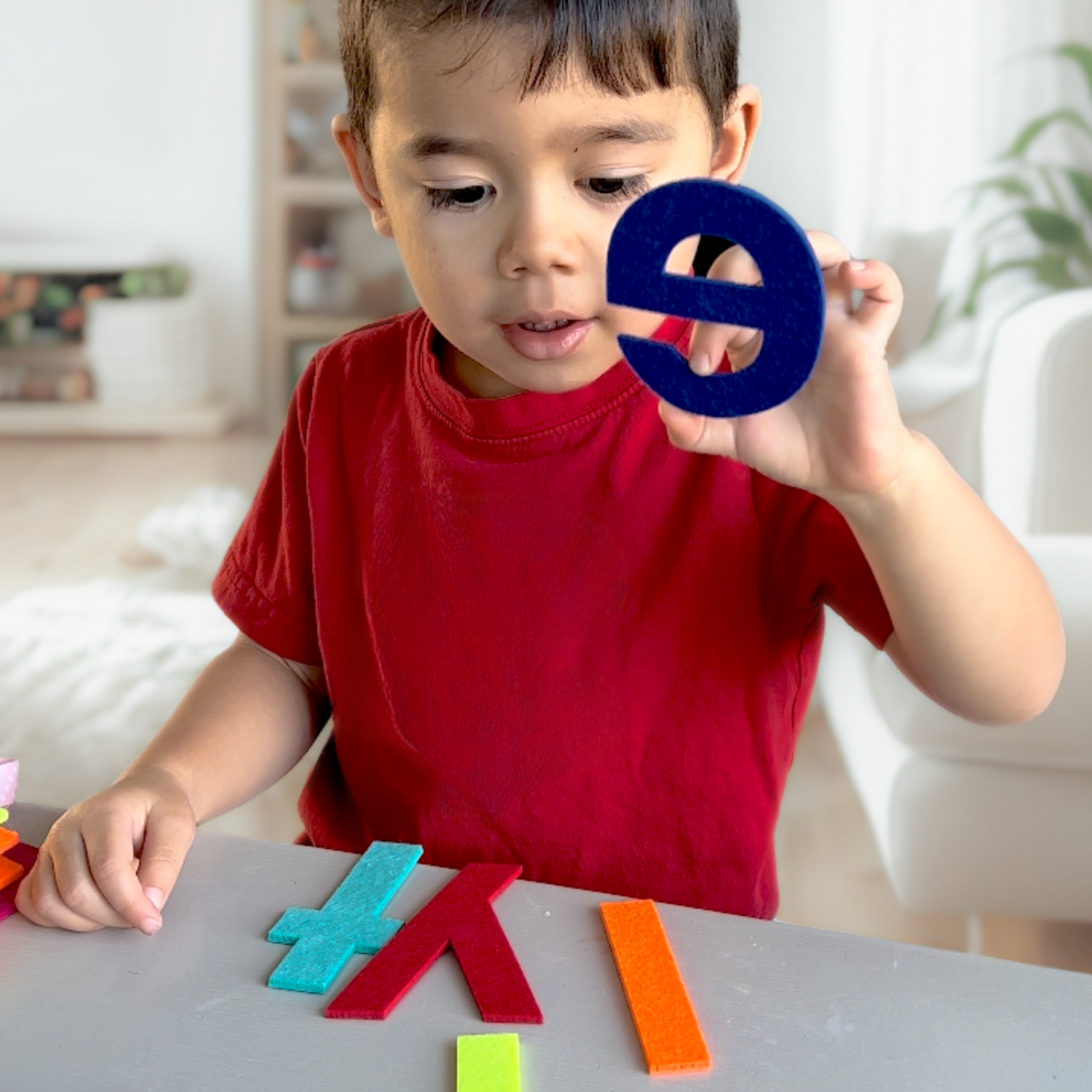 Child playing with colorful letters on a table in a home setting