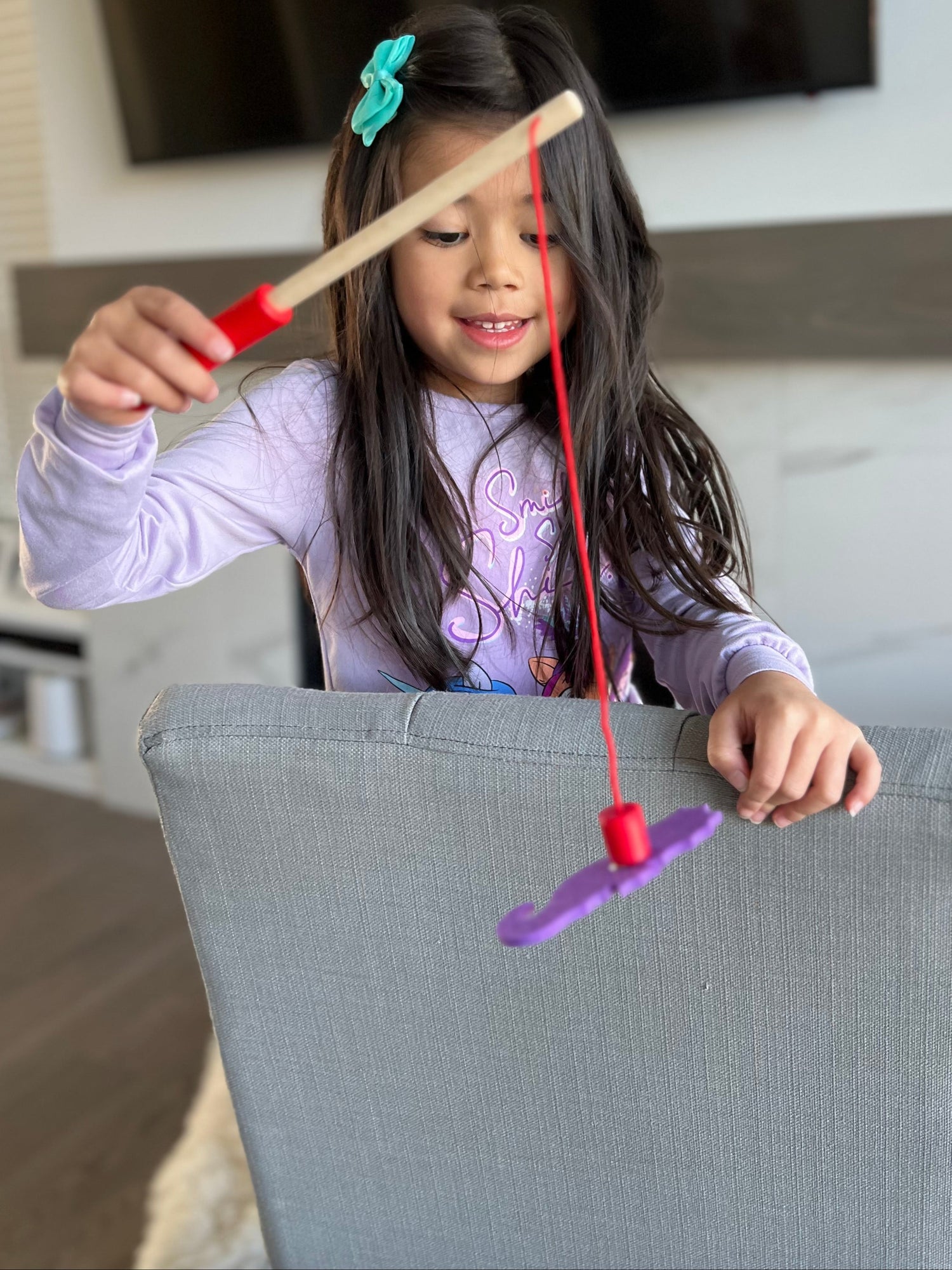Young girl playing with a fishing game in a hotel room